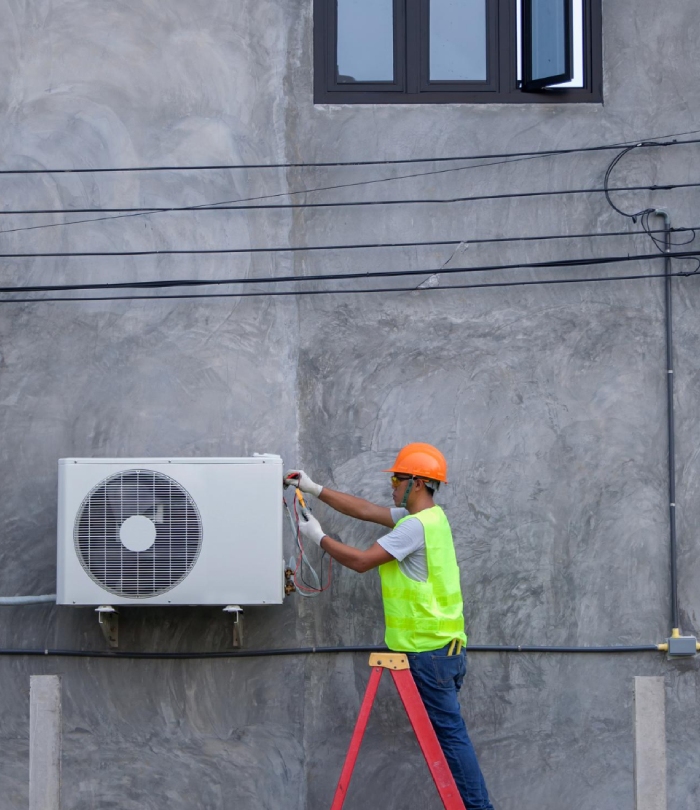 Technicien installant une unité extérieure de climatisation